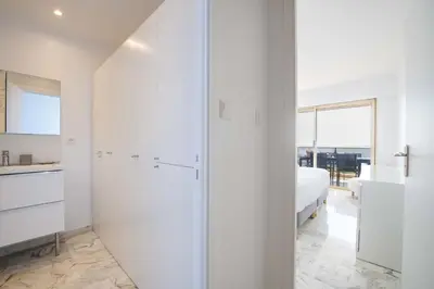 a white bedroom with a bed and a glass door at 2-Br Apartment Sea View & Pool Cannes Croix des Gardes in Cannes