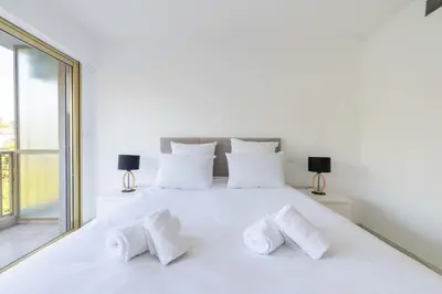 a white bedroom with a white bed with white pillows at 2-Br Apartment Sea View & Pool Cannes Croix des Gardes in Cannes