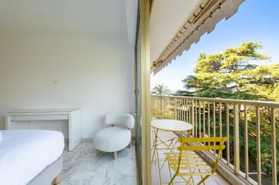 a bedroom with a balcony with a bed and a table and chairs at 2-Br Apartment Sea View & Pool Cannes Croix des Gardes in Cannes