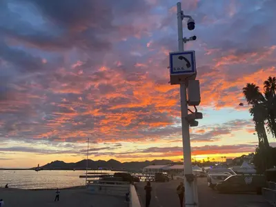 a sign on a pole with a sunset in the background at Le Baronne- Charmant studio climatisé au calme proche Plage et Palais des Festivals in Cannes