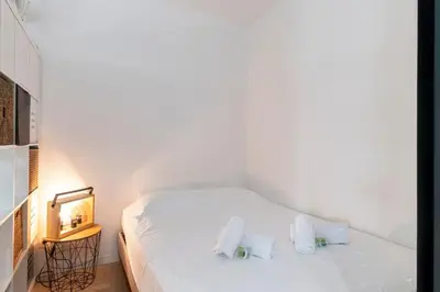 a white bed with two pillows in a room at Le Baronne- Charmant studio climatisé au calme proche Plage et Palais des Festivals in Cannes