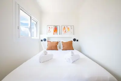 a white bedroom with a white bed with orange pillows at 2-Br Apartment with Terrace & Sea View Palm Beach Cannes in Cannes