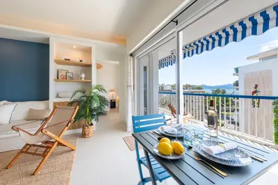 a living room with a table and chairs and a balcony at 2-Br Apartment with Terrace & Sea View Palm Beach Cannes in Cannes