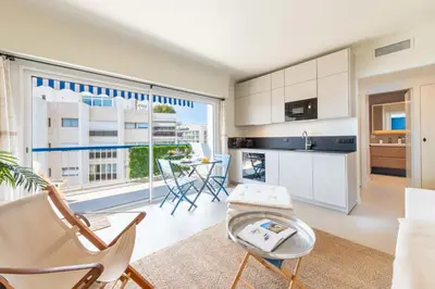 a living room with a table and chairs and a large window at 2-Br Apartment with Terrace & Sea View Palm Beach Cannes in Cannes