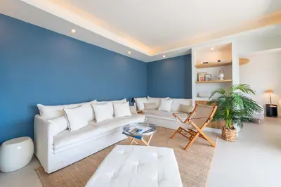 a living room with a white couch and a blue wall at 2-Br Apartment with Terrace & Sea View Palm Beach Cannes in Cannes