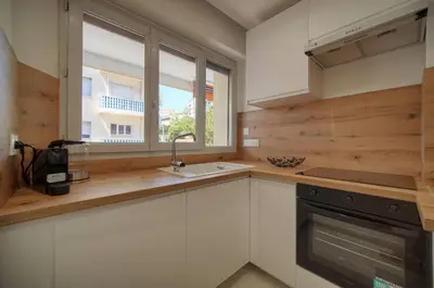 a kitchen with white cabinets and a sink and a window at FRGK Stanislas Apartment Terrace, Central Cannes AC & ULTRA FAST Wi-Fi in Cannes