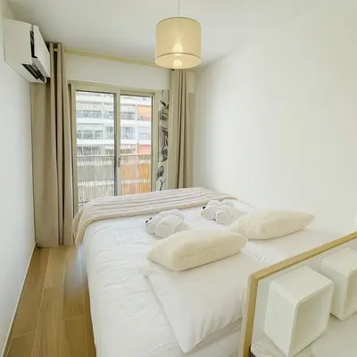 a white bedroom with a bed with towels on it at Newly Renovated 2BR Modern in Cannes