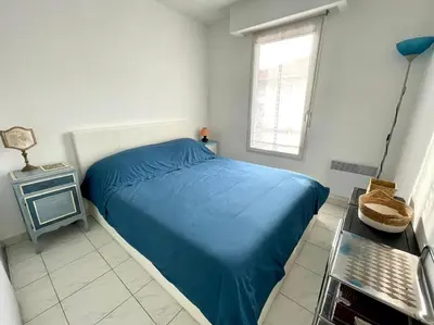 a bedroom with a blue bed and a window at Appart avec terrasse in Cannes