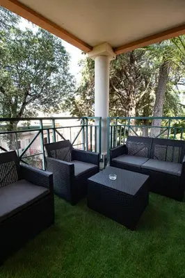 a porch with four chairs and a table on the grass at Appartement de standing, Piscine, Tennis, Plage in Cannes