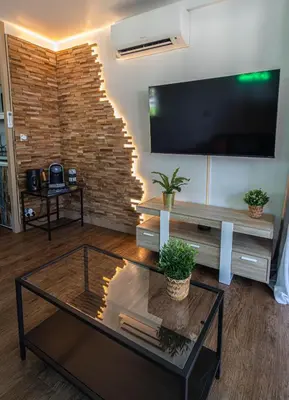 a living room with a flat screen tv on a brick wall at Appartement de standing, Piscine, Tennis, Plage in Cannes