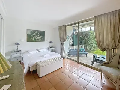 a bedroom with a white bed and a sliding glass door at 3-bedroom apartment on La Croisette with garden in Cannes