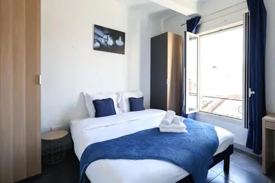 a bedroom with a bed with a blue blanket and a window at Studio, centre ville Cannes in Cannes