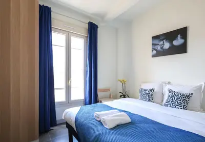 a bedroom with a bed with blue curtains and a window at Studio, centre ville Cannes in Cannes