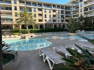 a swimming pool with lounge chairs and a large building at Le Beach 1 min plage , piscine , terrasse in Cannes