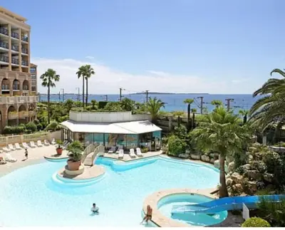 a pool at a resort with palm trees and the ocean at Palm d'Azur 459 in Cannes