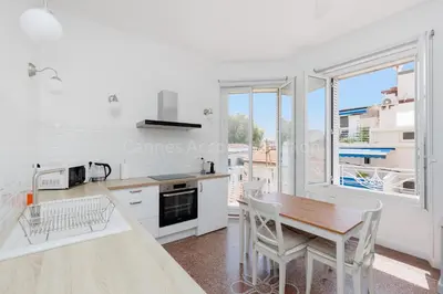 a white kitchen with a wooden table and chairs at Soeur in Cannes