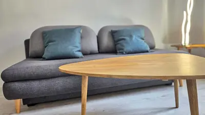 a couch with two blue pillows and a wooden table at LX154 Loft rénové lumineux - plein centre Cannes in Cannes