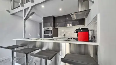 a kitchen with a counter with stools in it at LX154 Loft rénové lumineux - plein centre Cannes in Cannes