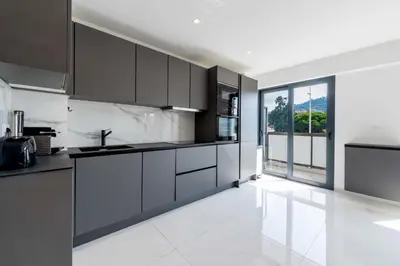 a kitchen with black cabinets and a white tile floor at Central 1-Br with Balcony Rue d’Antibes Cannes in Cannes
