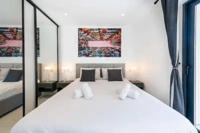 a white bedroom with a large white bed with mirrors at Central 1-Br with Balcony Rue d’Antibes Cannes in Cannes
