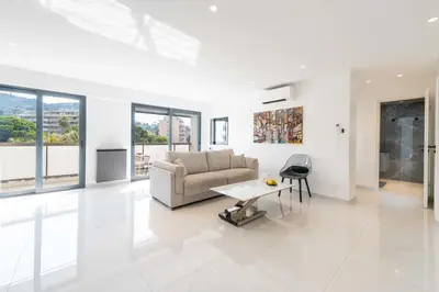 a white living room with a couch and a table at Central 1-Br with Balcony Rue d’Antibes Cannes in Cannes