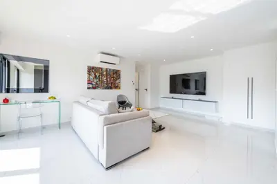 a white living room with a couch and a tv at Central 1-Br with Balcony Rue d’Antibes Cannes in Cannes