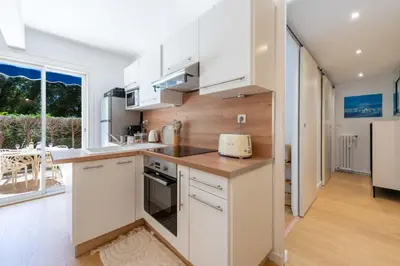 a kitchen with white cabinets and a large window at Ground-Floor Apartment with Private Garden Cannes in Cannes