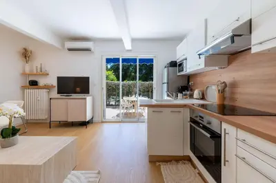 a kitchen with white cabinets and a large window at Ground-Floor Apartment with Private Garden Cannes in Cannes