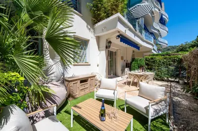 a patio with chairs and a table and a bottle of wine at Ground-Floor Apartment with Private Garden Cannes in Cannes