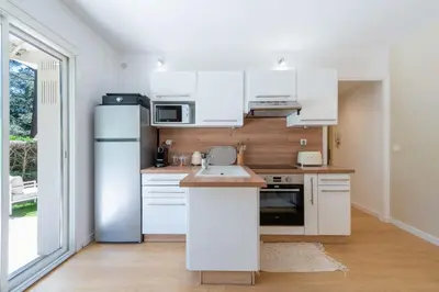 a kitchen with white cabinets and a refrigerator at Ground-Floor Apartment with Private Garden Cannes in Cannes