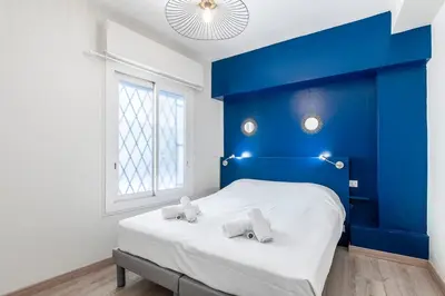 a bedroom with a blue headboard and a white bed at Le 45 Clémenceau - Superbe logement proche plages et Palais in Cannes