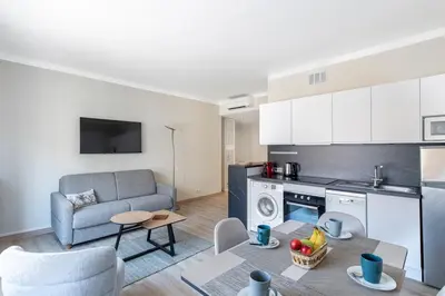 a living room with a couch and a kitchen at Le 45 Clémenceau - Superbe logement proche plages et Palais in Cannes