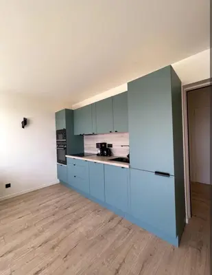 an empty kitchen with blue cabinets in a room at 3-room air-conditioned terrace, sea view in Cannes