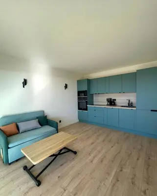 a living room with a blue couch and a table at 3-room air-conditioned terrace, sea view in Cannes