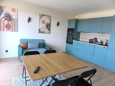 a living room with a table and a kitchen at 3-room air-conditioned terrace, sea view in Cannes