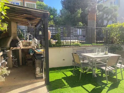 a table and chairs in a garden with a table and a fence at Villa piscine cannes 2 chambres in Cannes