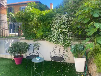 two chairs and a table in a garden with flowers at Villa piscine cannes 2 chambres in Cannes