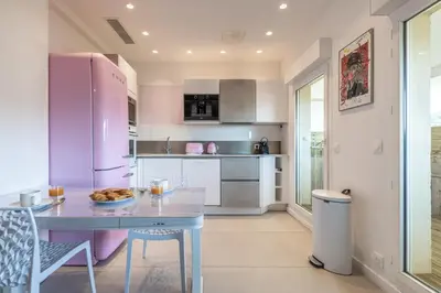 a kitchen with a table and a pink refrigerator at LB Vacation Rentals I Elegant Apartment with Terrace & Mezzanine in the heart of Cannes in Cannes