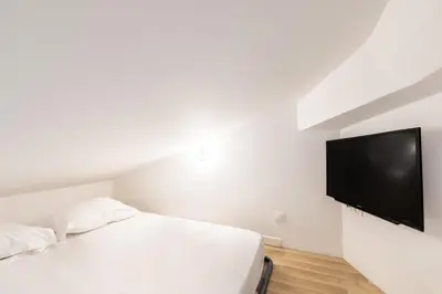 a bedroom with a bed and a flat screen tv at LB Vacation Rentals I Elegant Apartment with Terrace & Mezzanine in the heart of Cannes in Cannes