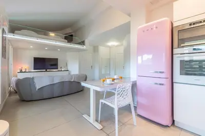 a kitchen with a table and a pink refrigerator at LB Vacation Rentals I Elegant Apartment with Terrace & Mezzanine in the heart of Cannes in Cannes