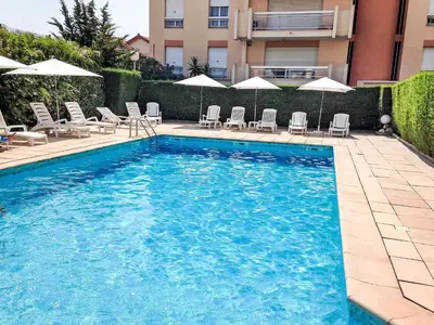 a swimming pool with chairs and umbrellas next to a building at Apartment Cannes Parc-2 by Interhome in Cannes