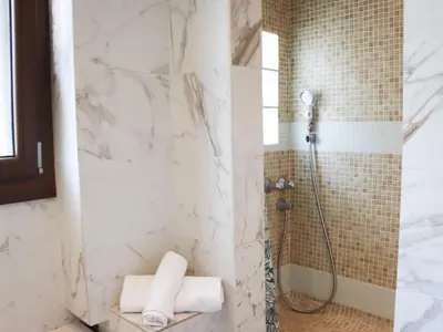 a bathroom with a shower with white marble walls at Apartment les Gemeaux by Interhome in Le Cannet