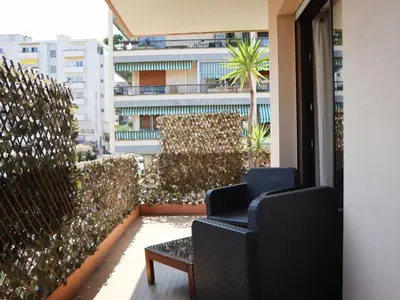 two chairs and a table on a balcony with a building at Apartment les Gemeaux by Interhome in Le Cannet
