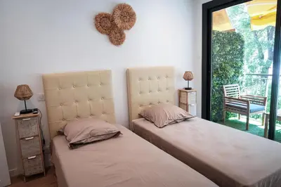 a bedroom with two beds and a window with a chair at Bali à Cannes in Cannes