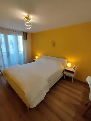 a bedroom with a large white bed and a yellow wall at Cannes Fleurs de Provence - proche centre-ville in Cannes