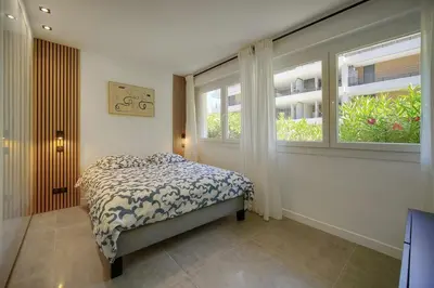 a bedroom with a bed and two windows at Modern 3BR with Patio, Walk to Beach and Croisette in Cannes