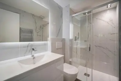 a white bathroom with a sink and a shower at Modern 3BR with Patio, Walk to Beach and Croisette in Cannes