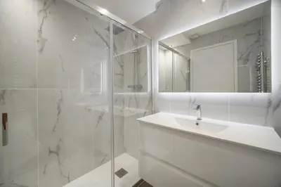 a white bathroom with a sink and a shower at Modern 3BR with Patio, Walk to Beach and Croisette in Cannes