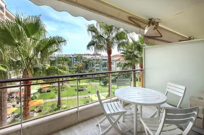 a balcony with a table and chairs and palm trees at REF 1233 - Cannes Croisette - Apartment for rent in Cannes