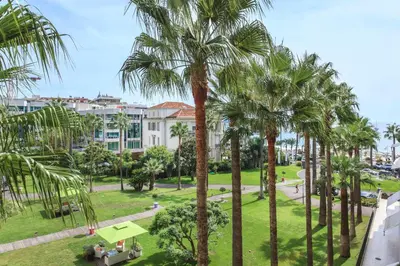a view of a park with palm trees and buildings at REF 1233 - Cannes Croisette - Apartment for rent in Cannes